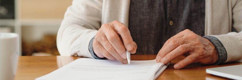 Close up of an elderly person's hands writing their end of life plan